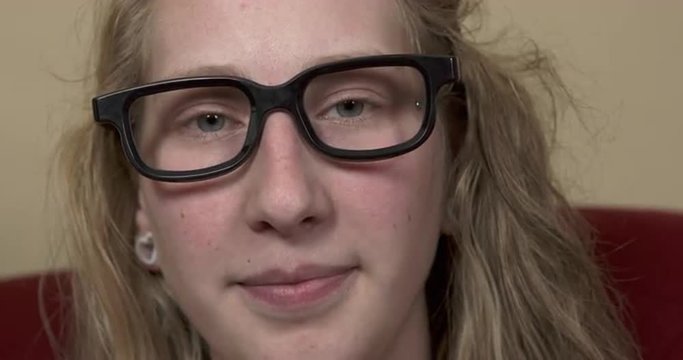 Young girl with nerdy black glasses has a free spirited look in her eyes.