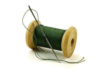 Wooden coil with threads and a needle on a white background