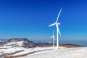 Fototapeta na wymiar Wind turbine and blue sky in winter landscape.