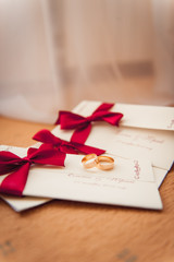wedding rings on invitation with a red ribbon