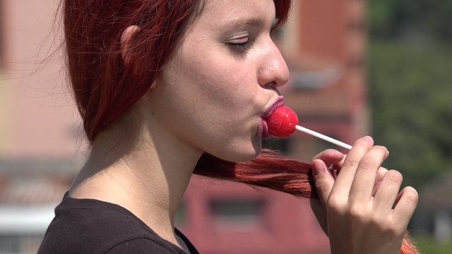 Redheaded Teen Female Eating Red Lollipop