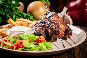 Grilled shish kebab served with fried chips and salad