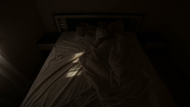 Happy young couple awakening and kissing and  in bed in pale vintage ligt