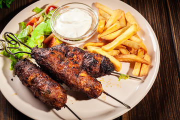 Grilled shish kebab served with fried chips and salad