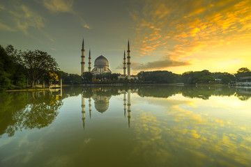 Fototapeta na wymiar The Beautiful Sultan Salahuddin Abdul Aziz Shah Mosque (also known as the Blue Mosque) with nature sunrise lighting and reflection..