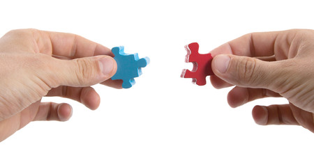 Close-up of hands trying to connect big jigsaw puzzle pieces