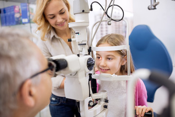 Mother and her daughter talk with eye specialist in clinic