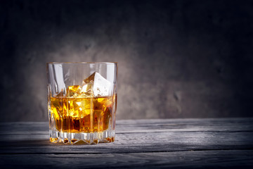 Faceted glass of whiskey with ice