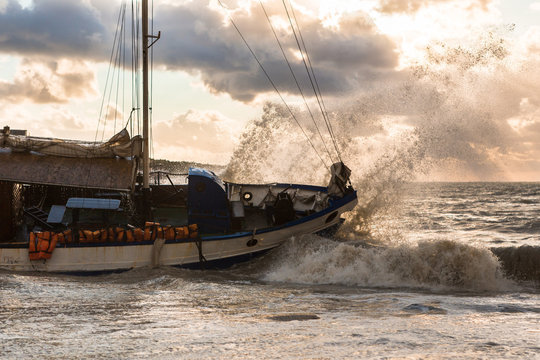 The ship ran aground during a storm. Sunset, water spray, high waves.