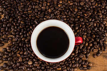 Cup of coffee and coffee beans on wooden table