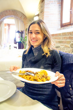 young woman Italian restaurant shows  serving tray full of steaming pasta