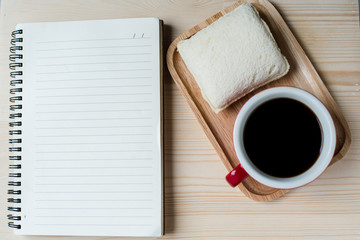 Tuna sandwich notebook and coffee red cup on pine wood