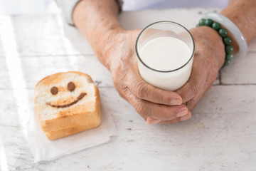 Senior woman's hands holding a glass of milk.