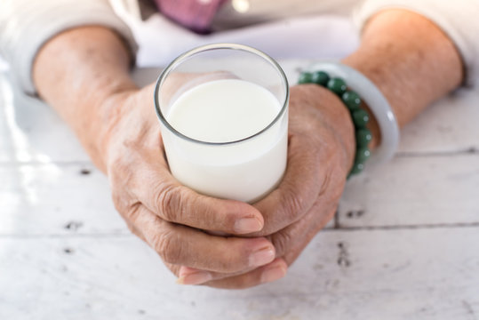 Senior woman's hands holding a glass of milk.
