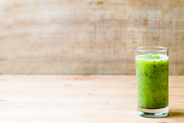 Healthy green smoothie in a glass on old wood.