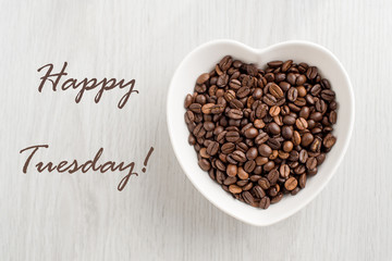 Happy Tuesday note and coffee bean in a bowl in the form of hear