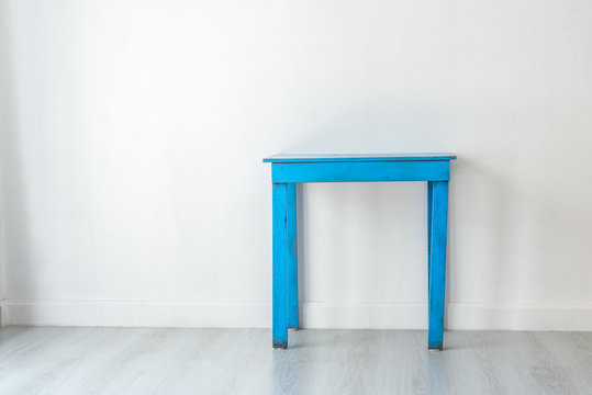 Old and dirty blue table in white room.