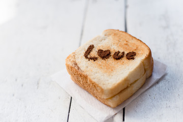 Love message on Bread sliced on white wooden background.