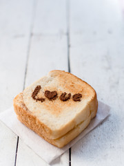 Love message on Bread sliced on white wooden background.