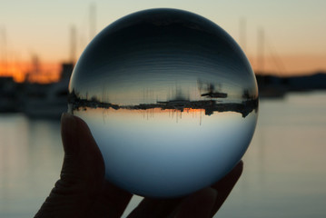 Fototapeta na wymiar Holding crystal ball with boats and sunset in reflection