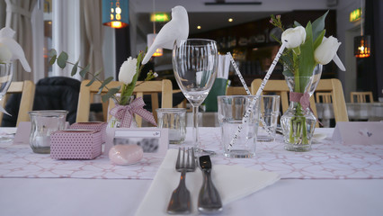 A table decoration with straws, glasses and birds from a low perspective