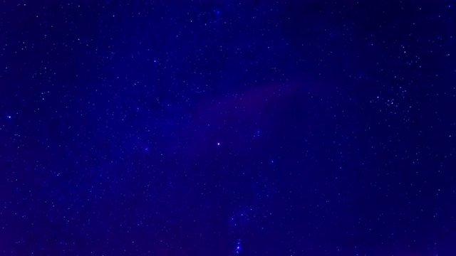 timelapse of an amazing starry blue sky at night with some clouds and planes in front of the milky way