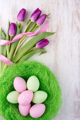 easter eggs and flowers over white wooden table
