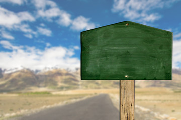 Green sign board with road to snow hill background