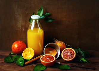 Still life with orange fruit and juice in bottle