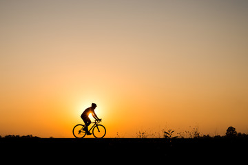 Silhouette of cyclist motion on sunset background