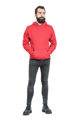 Serious young punker in red hooded sweatshirt looking away. Full body length portrait isolated over...