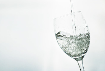 Filling a glass with water on light gray background 