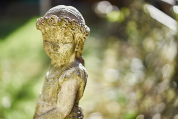 Figure of  pensive looking country girl with braided hair / Statue of Stone in peaceful garden