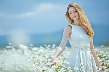 Fototapeta na wymiar Beautiful young woman in a camomile field 
