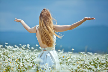 Beautiful young woman in a camomile field 