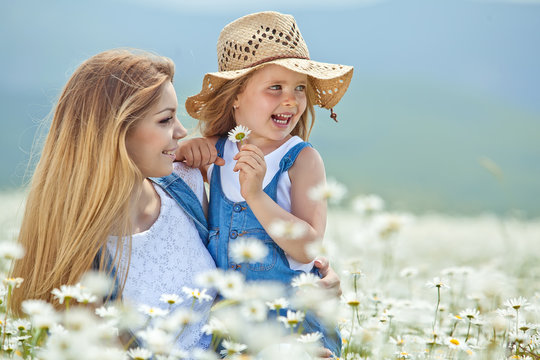 Beautiful young woman with kid in a camomile field 