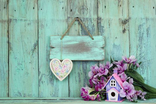 Blank sign with heart by flowers and birdhouse
