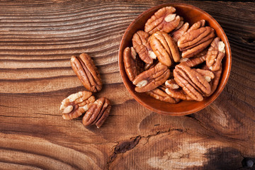 pecan nuts in a rustic scoop against a grunge wood background