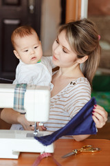 Mother with a baby shows her work, sewing at home. Raising children, child care, nanny.
