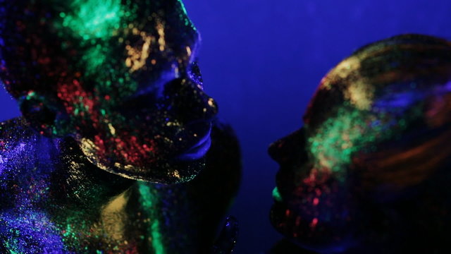 man and woman in makeup glow in ultraviolet light