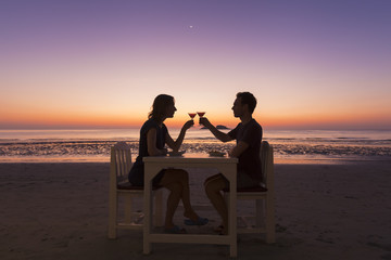 Romantic diner at a beach restaurant, couple, sunset, tropical r