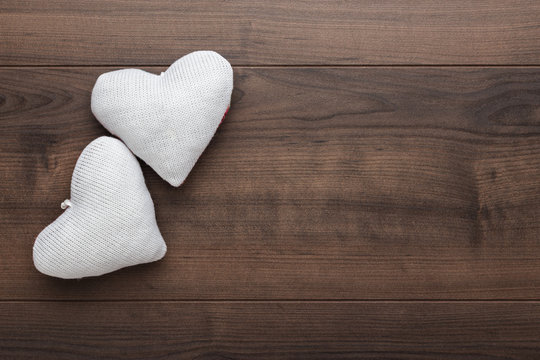 two knitted heart shapes on the wooden table