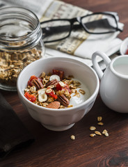 Natural yoghurt and homemade granola - healthy tasty breakfast. On a dark wooden background