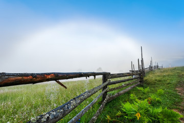 Fototapeta na wymiar Carpathian Mountains. Overcast with a white rainbow, fence with cobwebs.