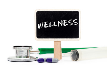 WELLNESS concept with text on chalkboard with stethoscope, syringe and pills
