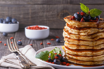 Stack of pancakes with fresh blueberry, goji  and maple syrup.