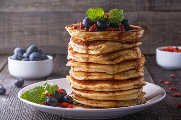 Stack of pancakes with fresh blueberry, goji  and maple syrup.