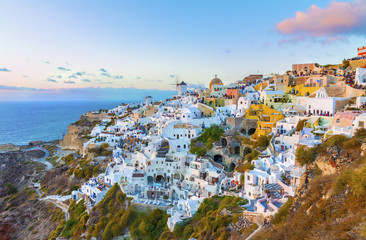 Charming Oia village in last rays of sunset.Panoramic view from a height above the houses, villas and the Mediterranean sea.Beautiful natural landscape.Santorini (Thira) island.Cyclades.Greece.Europe.