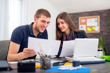Beautiful smiling young  businesswoman sitting working with a young man in a busy office