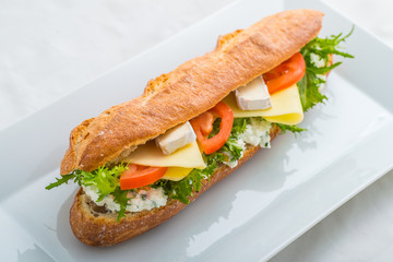 long sandwich with tofu, cheese, tomatoes and lettuce. Isolated on white background